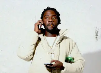 A man holding a cell phone and wearing a white jacket.