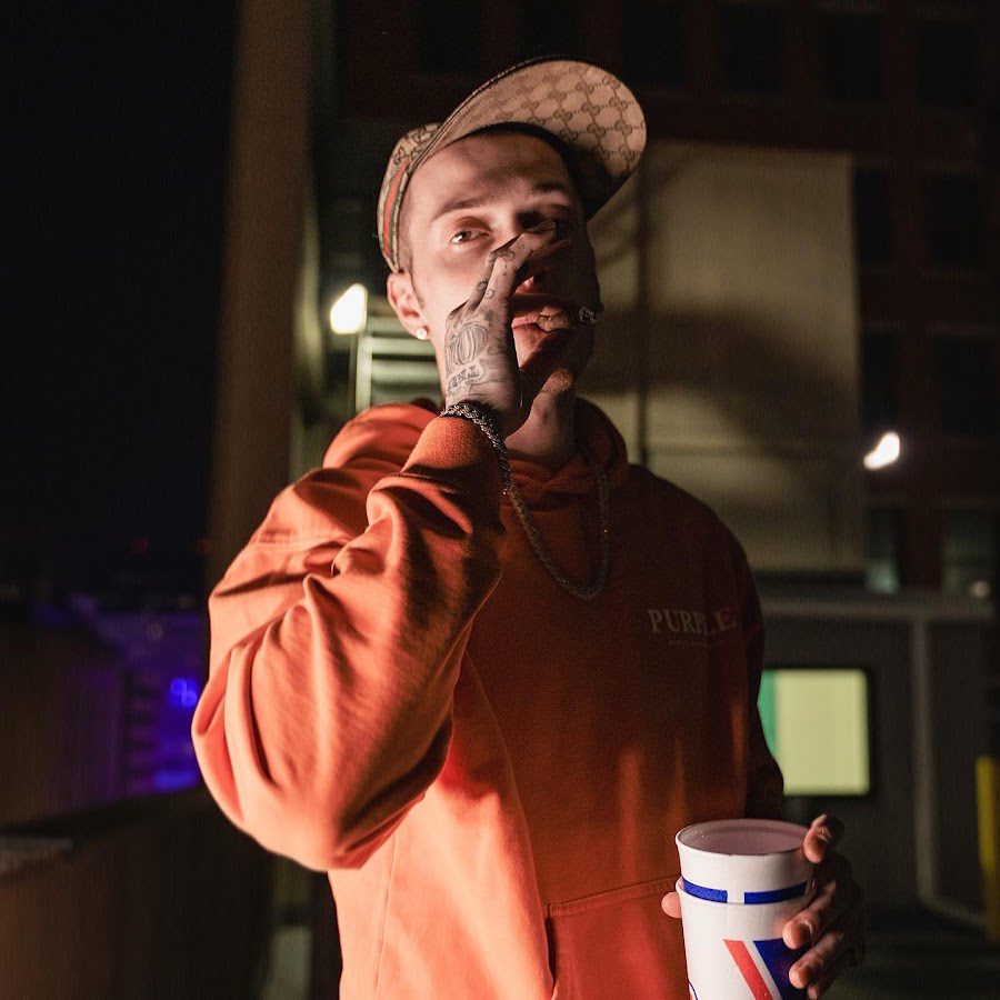 A man in an orange jacket holding onto a cup