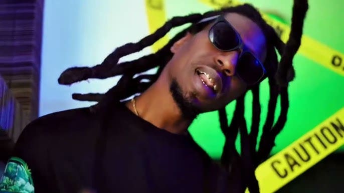 Man with dreadlocks wearing sunglasses, caution tape.