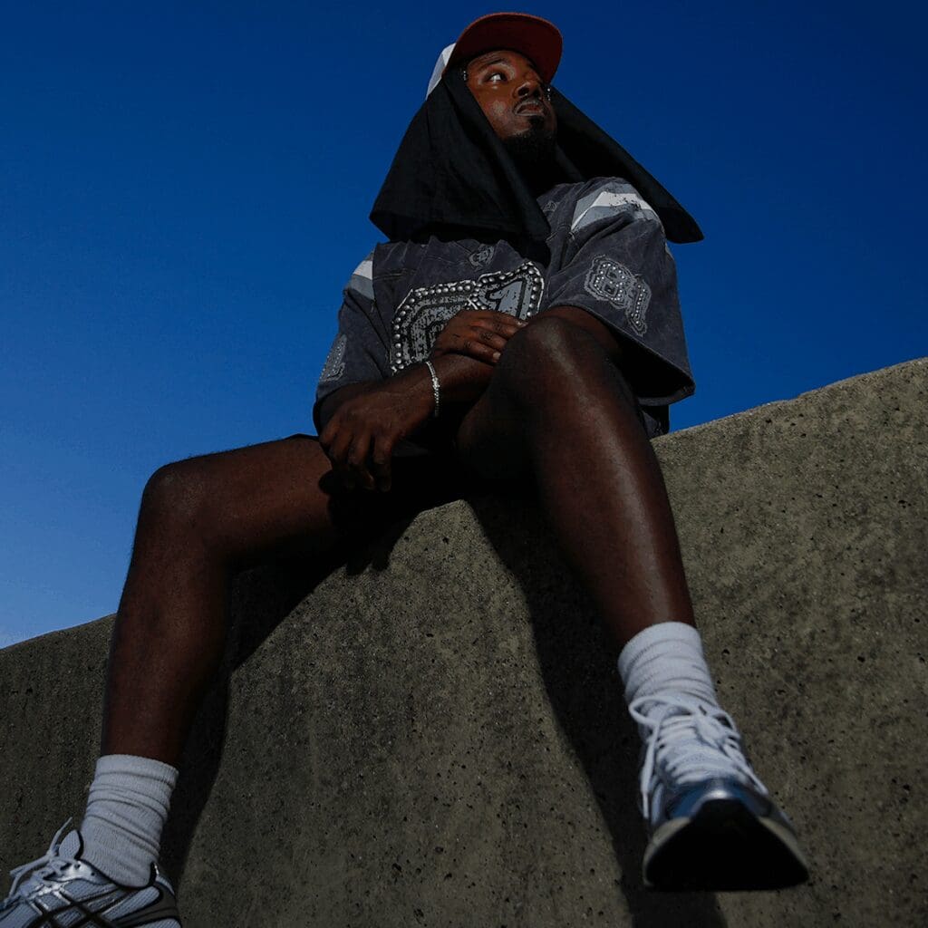 Person sitting on ledge under clear sky.