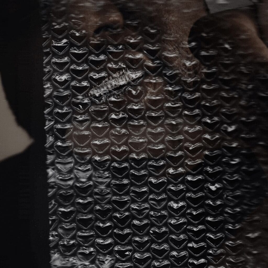 Smiling man behind bubble wrap sheet.