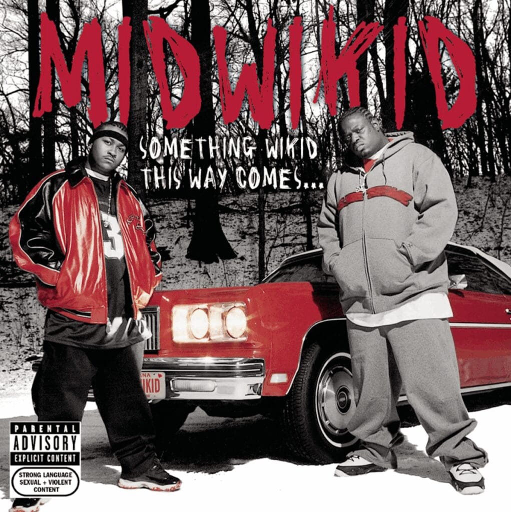 Two men standing by a red car.